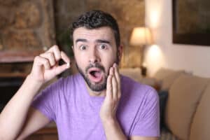 Adult man holds a tooth that has fallen out of his mouth, meaning that he has a vacancy to fill with help from restorative dentistry