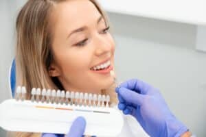 Woman having her teeth color-matched for veneers by her dentist.